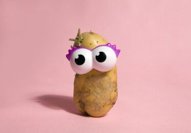 A potato with a pair of toy eyes to resemble a potato head.