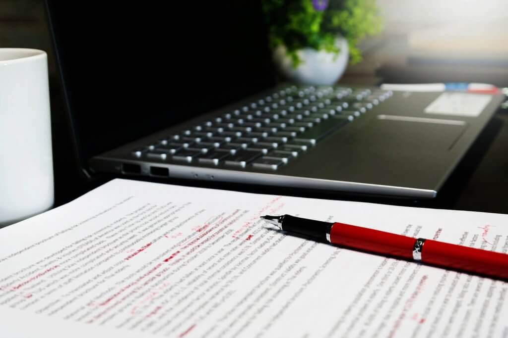 proofreading on paper with a laptop and pen